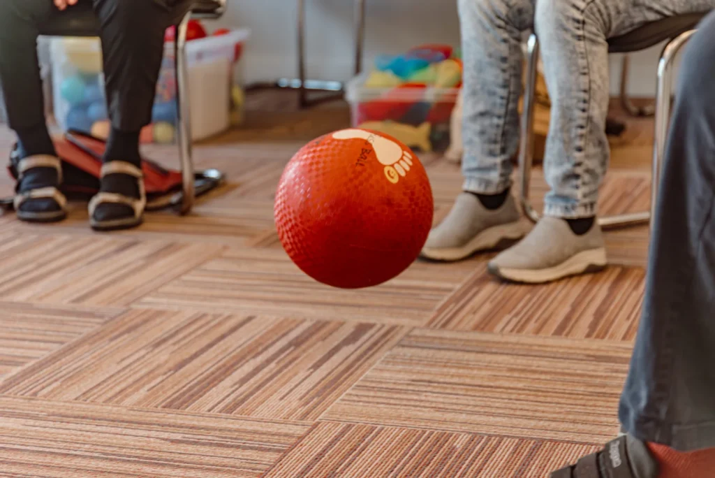 Roter Ball rollt zwischen den Füßen der Gruppe