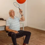 Teilnehmer spielt im Sitzen mit Ball und Schläger