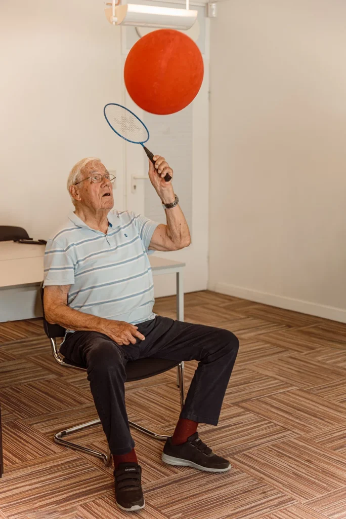 Teilnehmer spielt im Sitzen mit Ball und Schläger